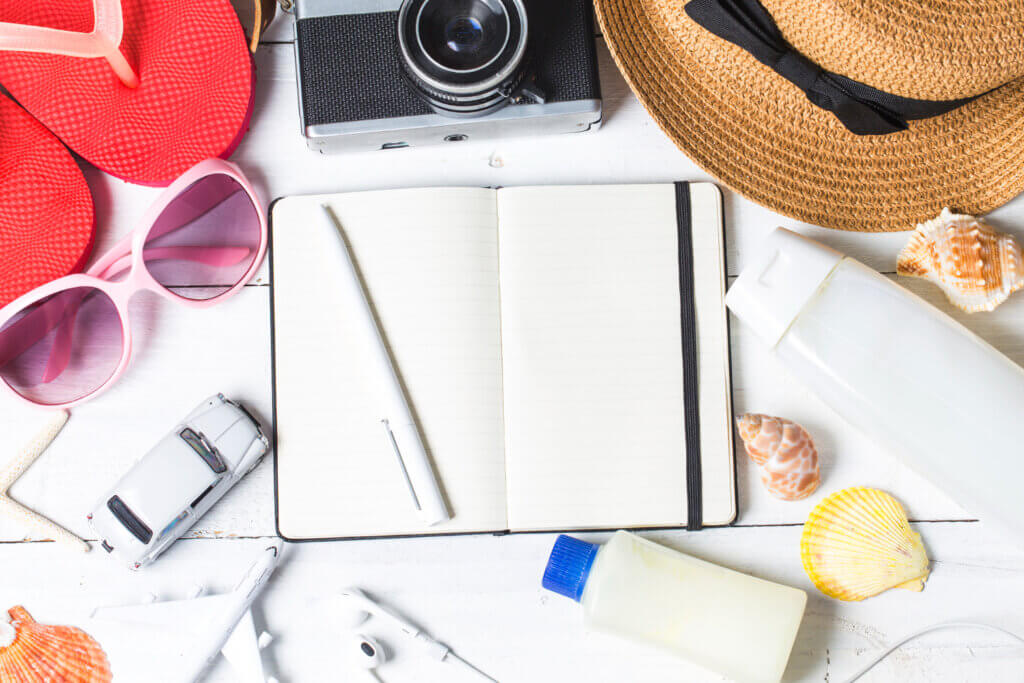 Excursão em parque aquático: tudo o que você precisa saber! | caderno, caneta, óculos, chapéu, chileno e protetor solar sobre uma mesa | Acquamania